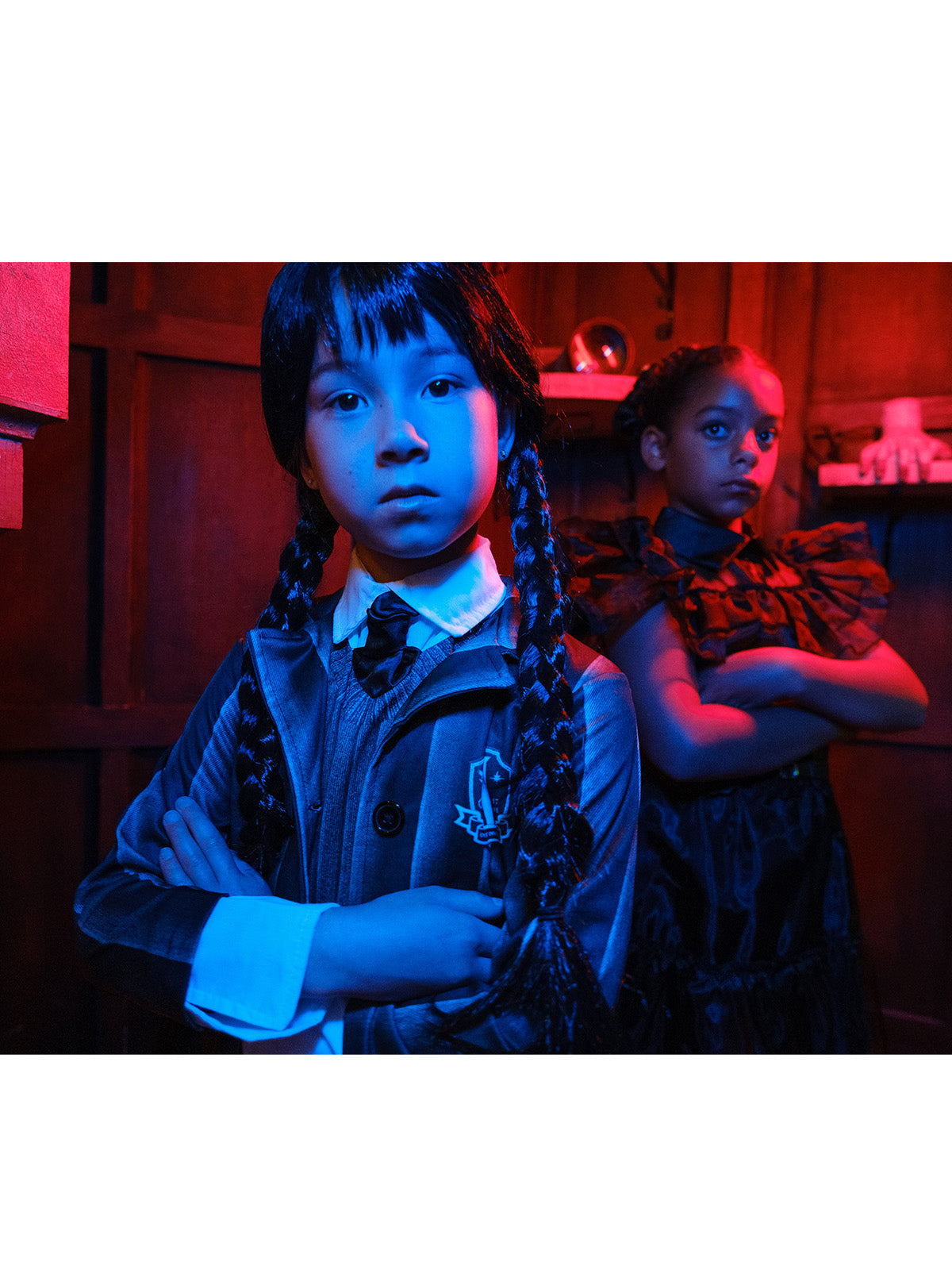 Close-up of a girl in the Nevermore Academy jacket with crest and striped tie under red lighting