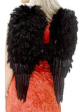 Woman wearing large black feather angel wings, back view