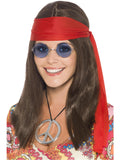Woman wearing a long brown hippie wig, red headscarf, blue round glasses and peace sign medallion