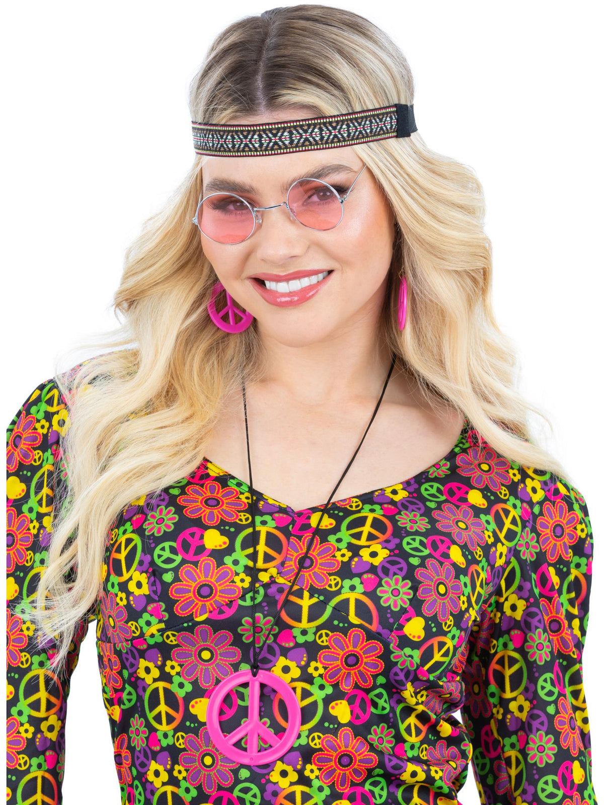 Woman wearing pink-lens round glasses, patterned headband and pink peace sign earrings and necklace