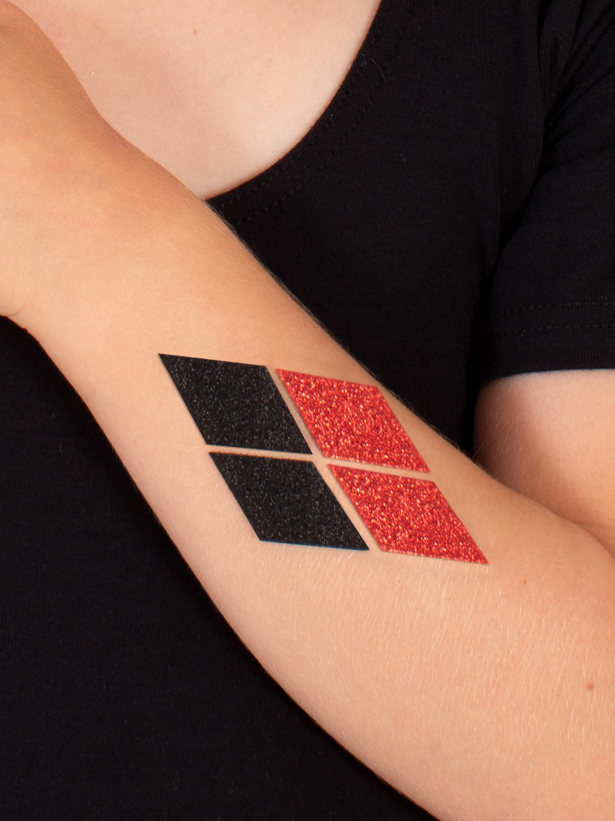 Red and black glitter diamond Harley Quinn tattoo on a forearm
