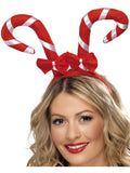 Woman wearing a headband with two red and white striped candy canes and red bows