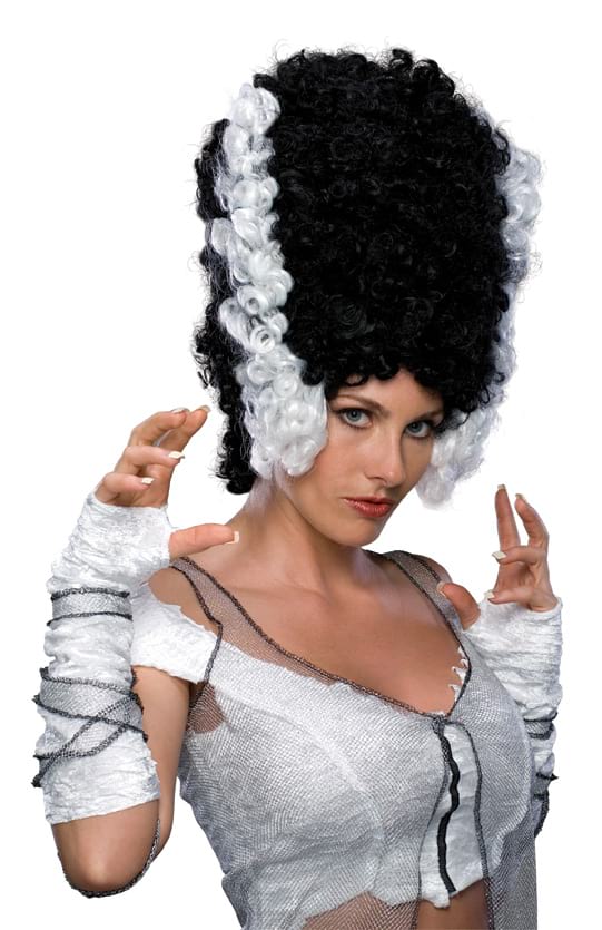 Woman wearing a tall curly black beehive wig with white side streaks