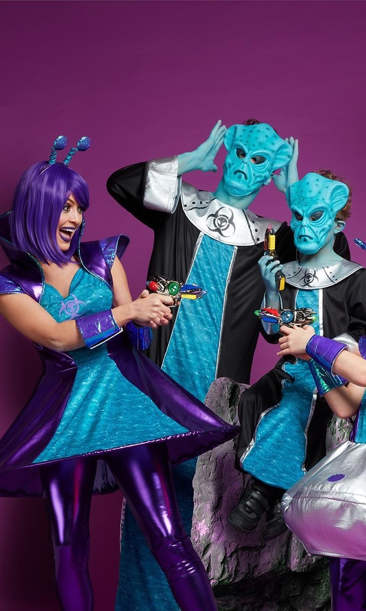 A family dressed in purple and blue alien costumes holding laser guns