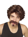Man in a black singlet wearing a brown curly wig with matching moustache and goatee