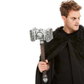 Man holding a silver war hammer prop with a brown handle