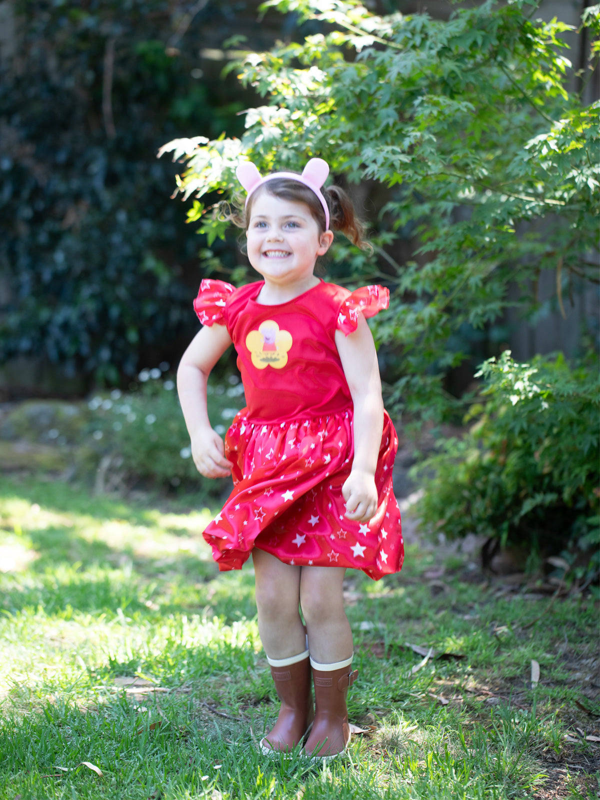 Girl twirling in the red Peppa Pig Deluxe dress with piggy ears headband