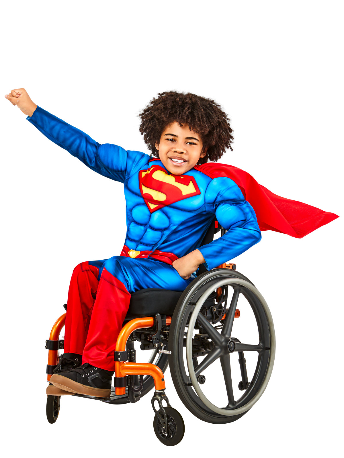 Boy using a wheelchair, wearing an adaptive Superman costume with padded muscle top, S emblem and red cape