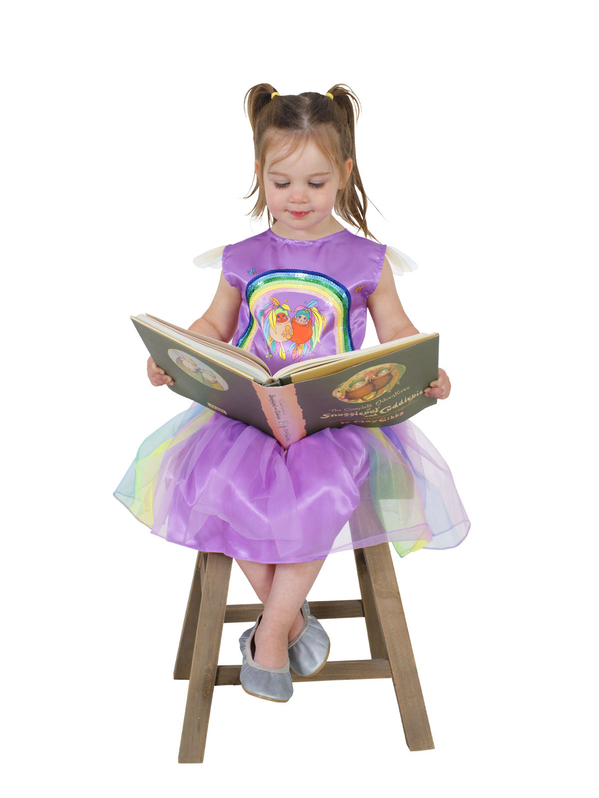 Girl sitting on a stool reading, wearing the Gumnut Baby Kasey Rainbow tutu dress