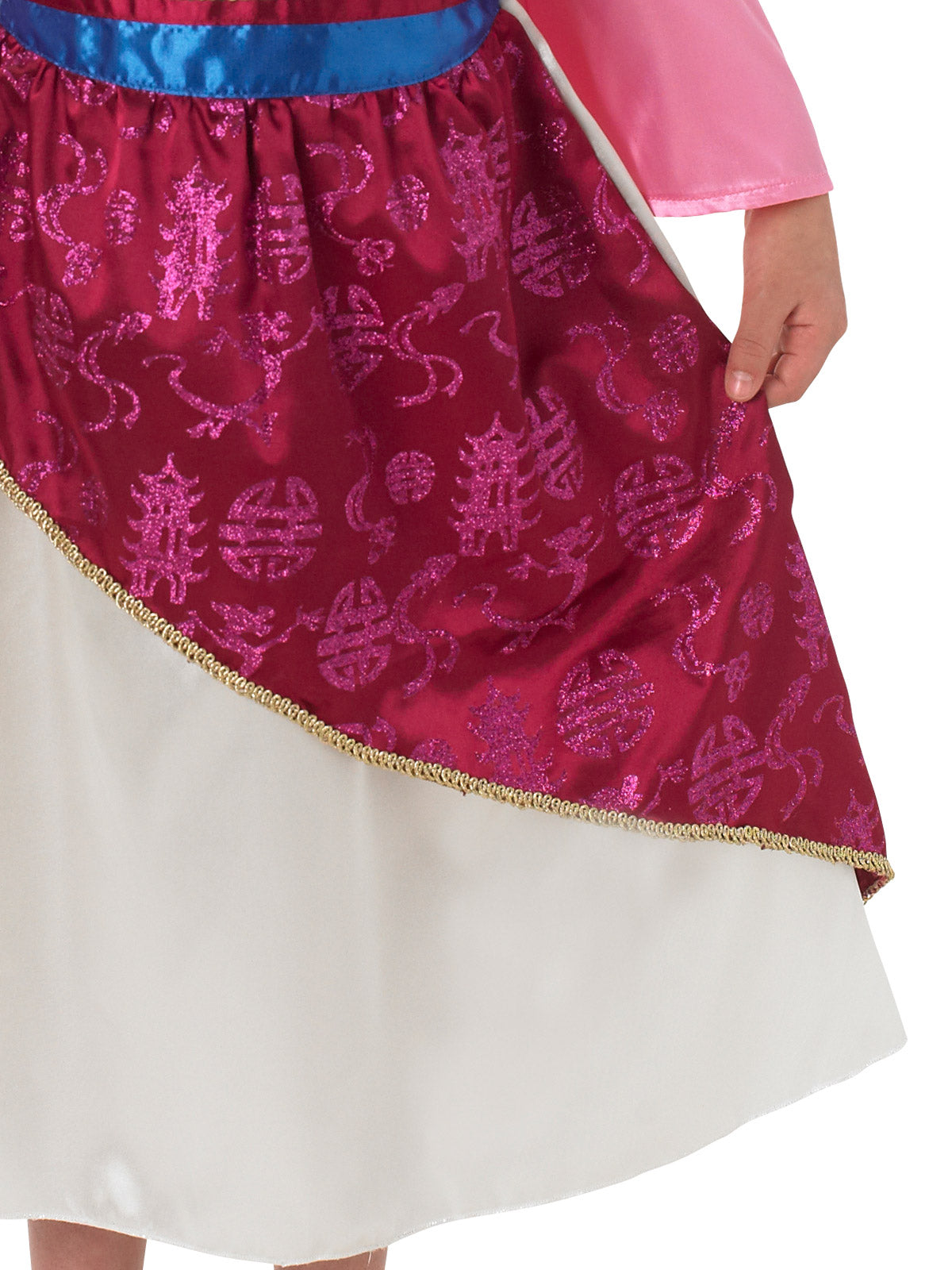 Close-up of the Mulan dress's magenta glitter overskirt with gold trim over a cream skirt