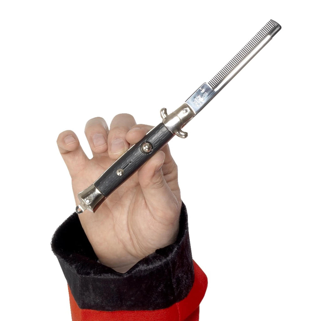 Hand holding a black and silver 50s flick comb that opens like a switchblade