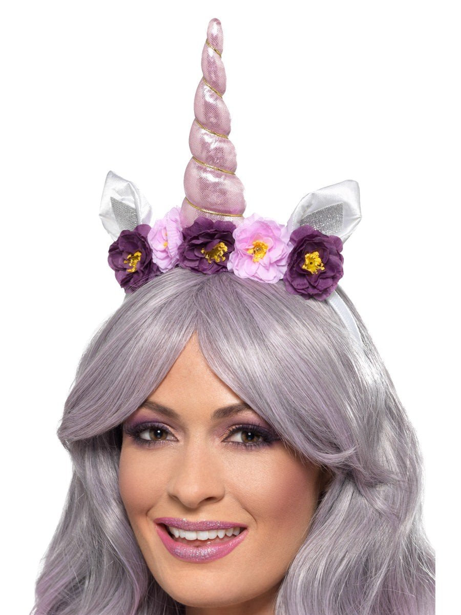 Woman wearing a unicorn headband with pink horn, white ears and purple and pink flowers